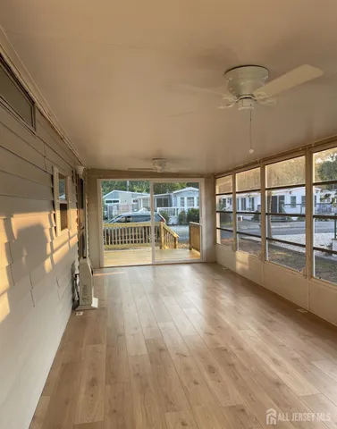 a view of empty room with wooden floor and fan