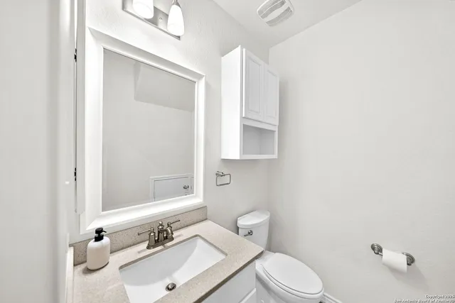 a bathroom with a sink vanity mirror and toilet