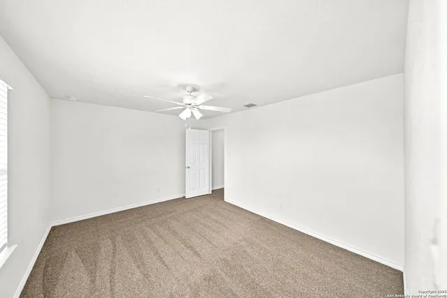 an empty room with a fan & a window