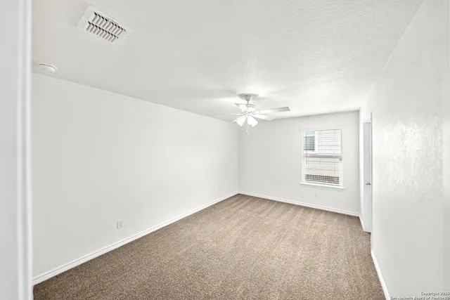 an empty room with windows and chandelier fan