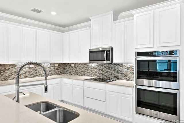 a kitchen with white cabinets a sink and stainless steel appliances