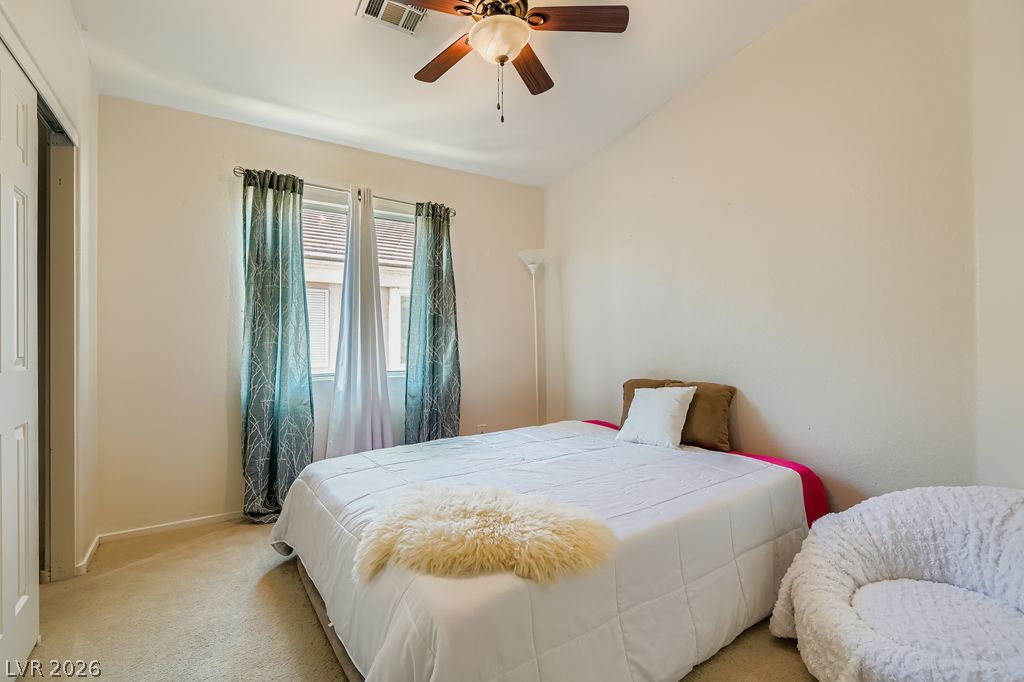 1586 Rusty Ridge Lane Henderson, NV 89002 - Photo 5 of 11 Well-lit sleeping quarters with a vaulted ceiling and soft carpeted flooring.