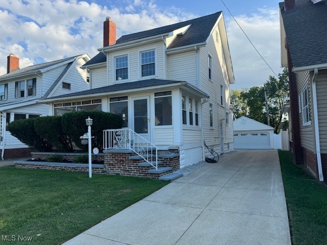 View of front of house with a front yard, an outdoor structure, and a garage