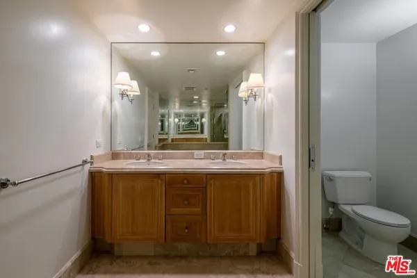 a view of a bathroom with a granite countertop sink a toilet and a mirror