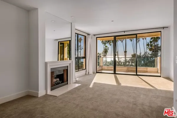 a view of an empty room with glass door and a fireplace