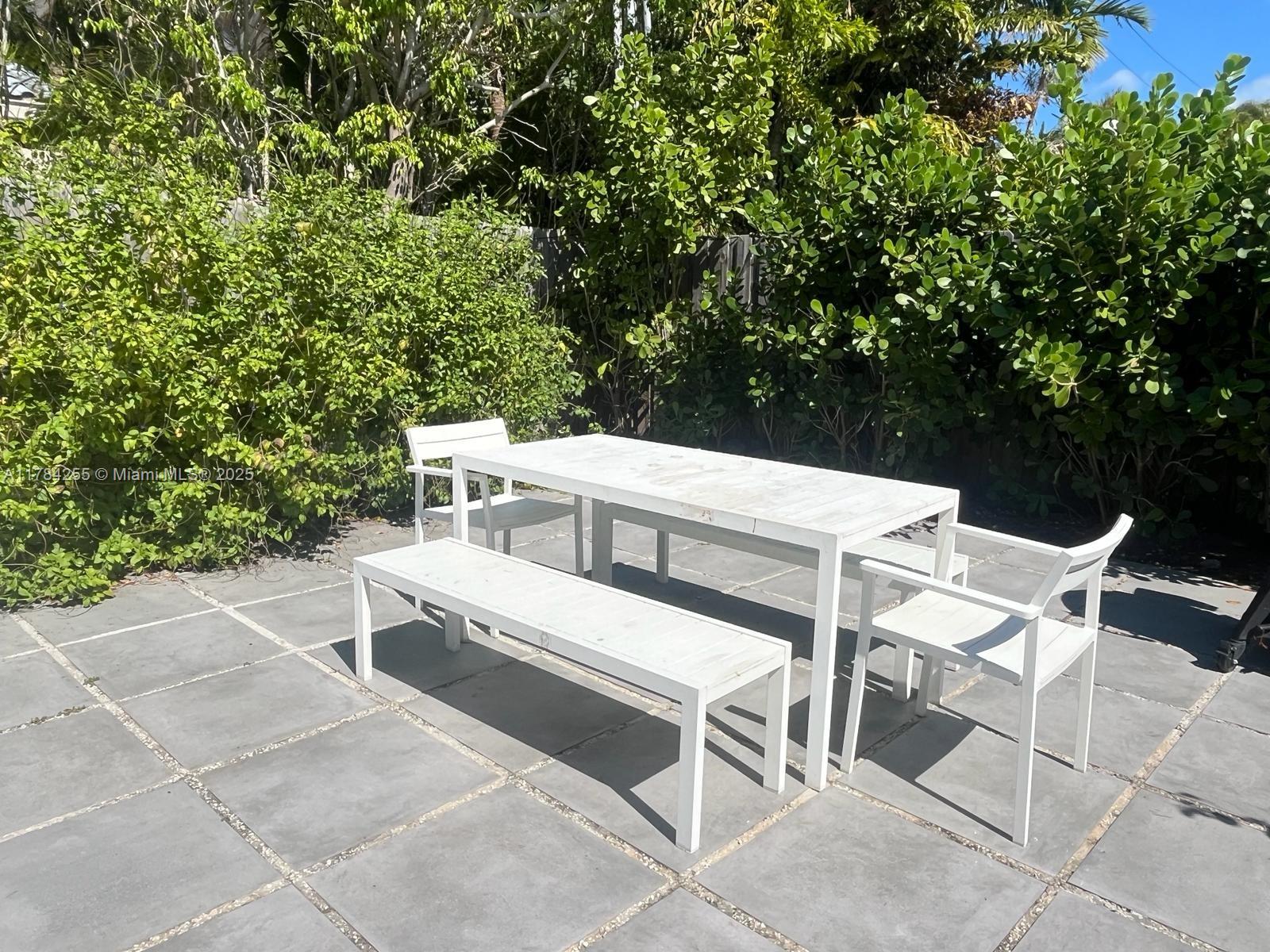 Tropical Isle Homes Key Biscayne, FL 33149 - Photo 18 of 38 a view of a patio with table and chairs with wooden fence and plants