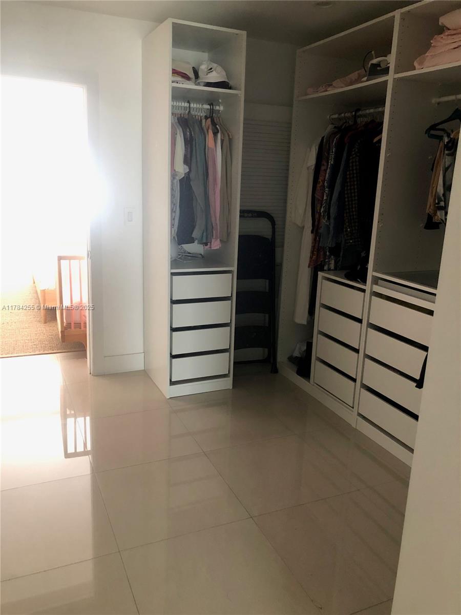 Tropical Isle Homes Key Biscayne, FL 33149 - Photo 28 of 38 a view of walk in closet with clothes and shoes