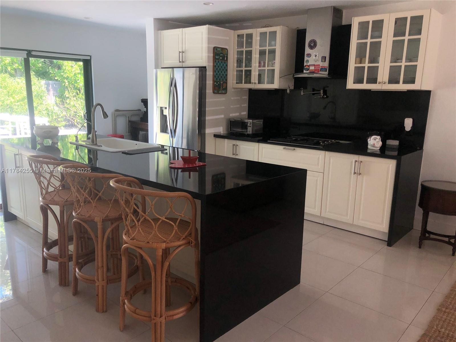 Tropical Isle Homes Key Biscayne, FL 33149 - Photo 33 of 38 a kitchen with stainless steel appliances granite countertop a refrigerator and a stove top oven