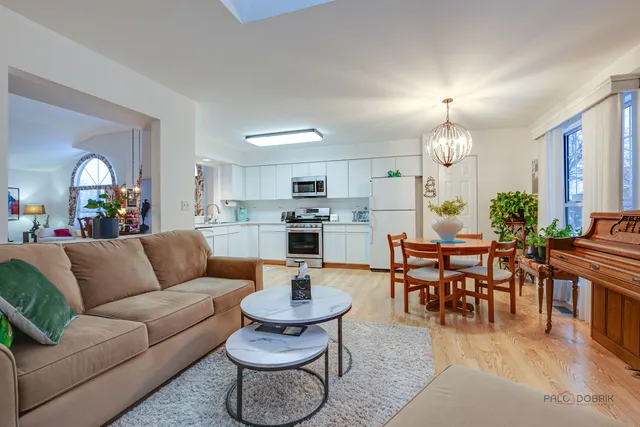 a living room with furniture kitchen view and a wooden floor