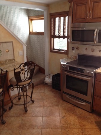 162 Beaconsfield Road Worcester, MA 01602 - Photo 3 of 7 a kitchen with a stove a microwave and wooden cabinets