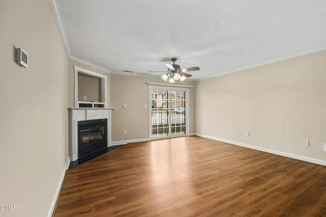 a view of an empty room with wooden floor fireplace and a window