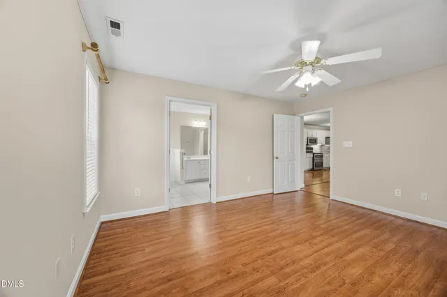 a view of an empty room with wooden floor and a window