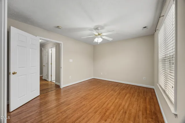 a view of an empty room with wooden floor and a window