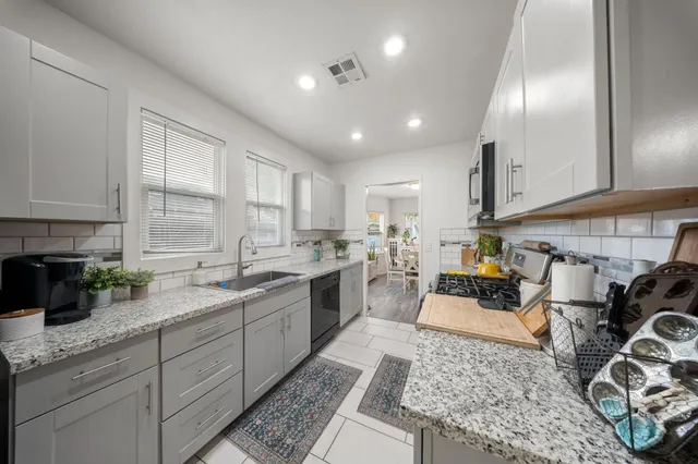 a kitchen with stainless steel appliances granite countertop a sink stove and cabinets