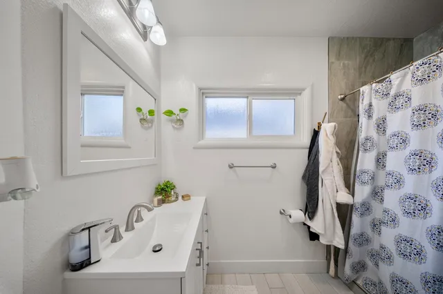 a bathroom with a sink and mirror with bathtub