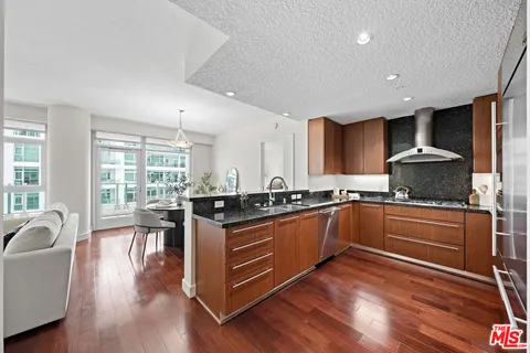 a kitchen with stainless steel appliances granite countertop wooden floors and view living room