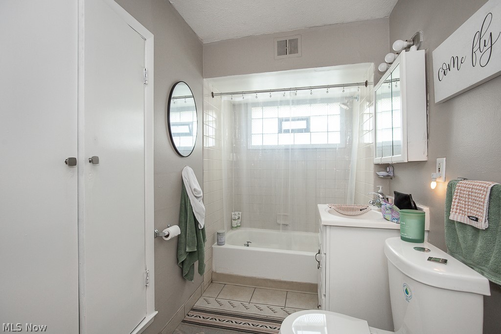 1405 Sheffield Road Cleveland, OH 44121 - Photo 9 of 29 Full bathroom with tile patterned flooring, a textured ceiling, tiled shower / bath combo, toilet, and vanity