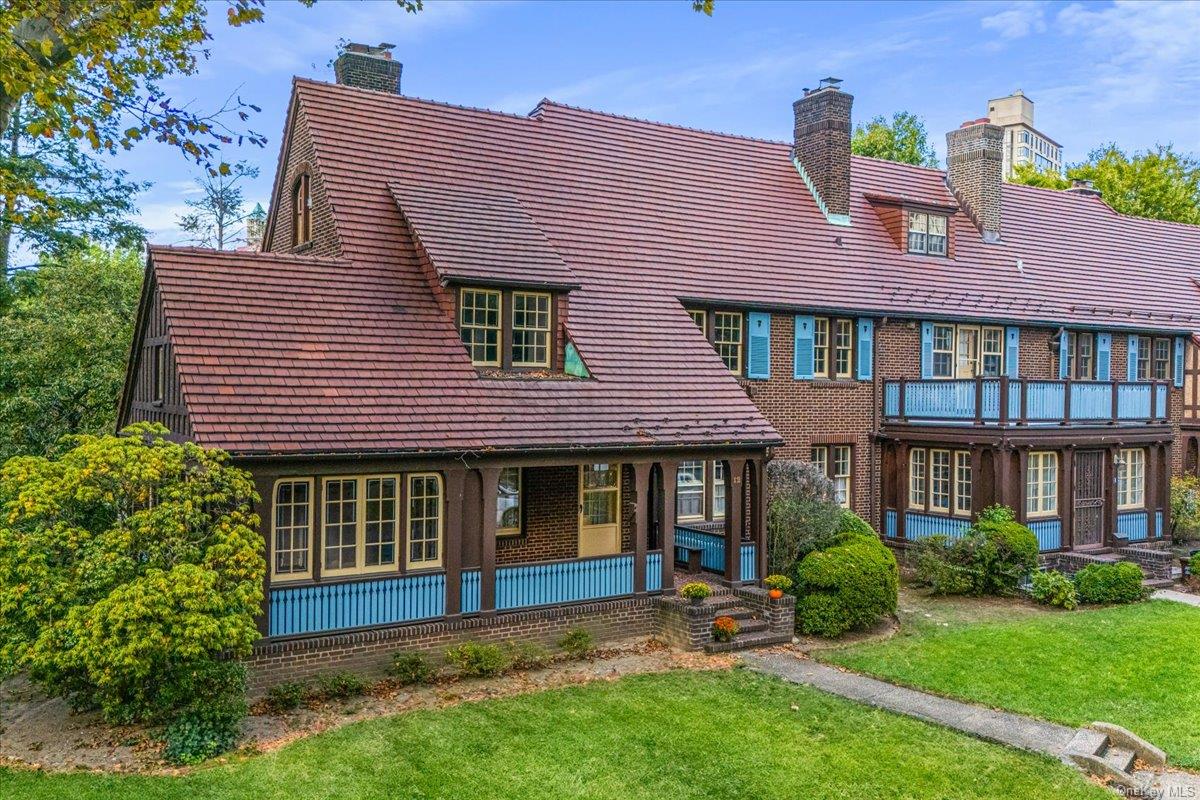 Back of house with brick siding, a lawn, a porch, and a chimney