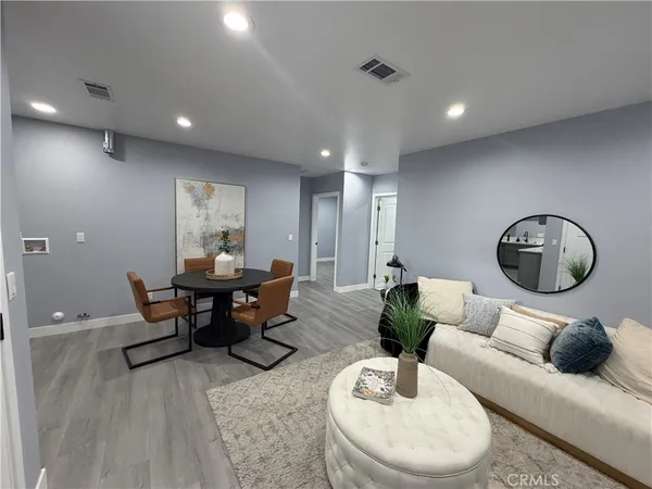 a living room with furniture a mirror and a wooden floor