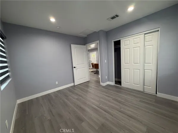 an empty room with wooden floor & windows and bathroom