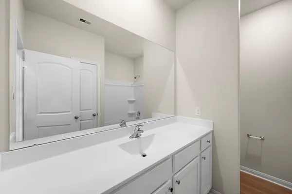 a view of an empty room with kitchen and window