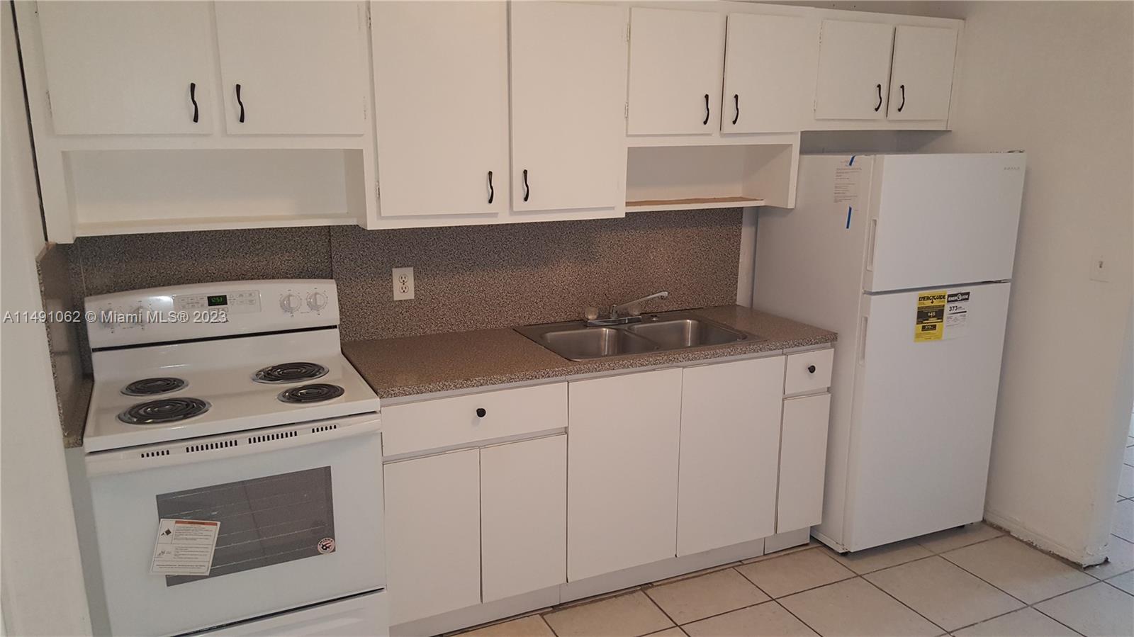 Miami-Dade County Miami, FL 33161 - Photo 13 of 31 a kitchen with white cabinets and white appliances
