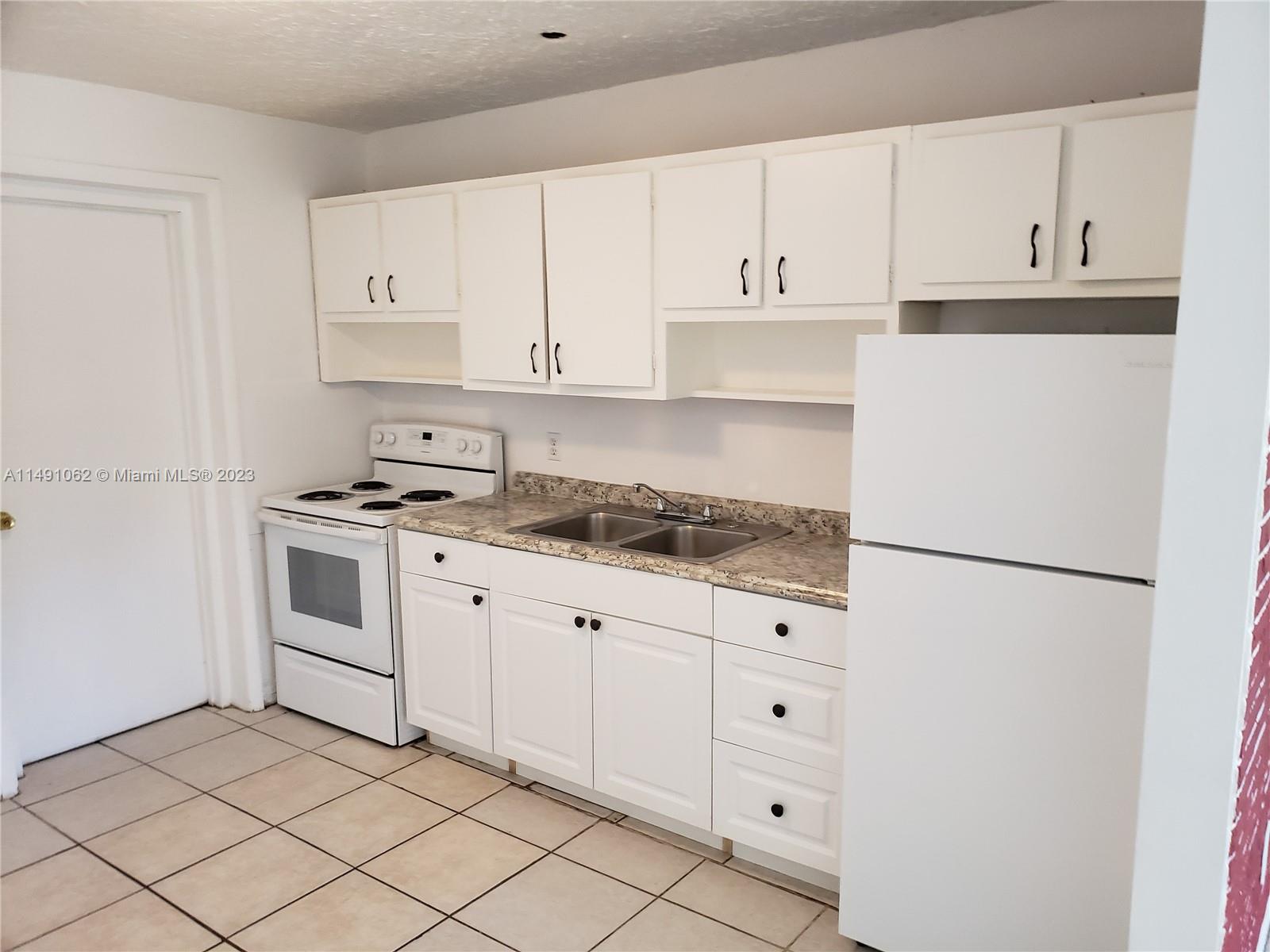 Miami-Dade County Miami, FL 33161 - Photo 18 of 31 a kitchen with granite countertop white cabinets and white appliances