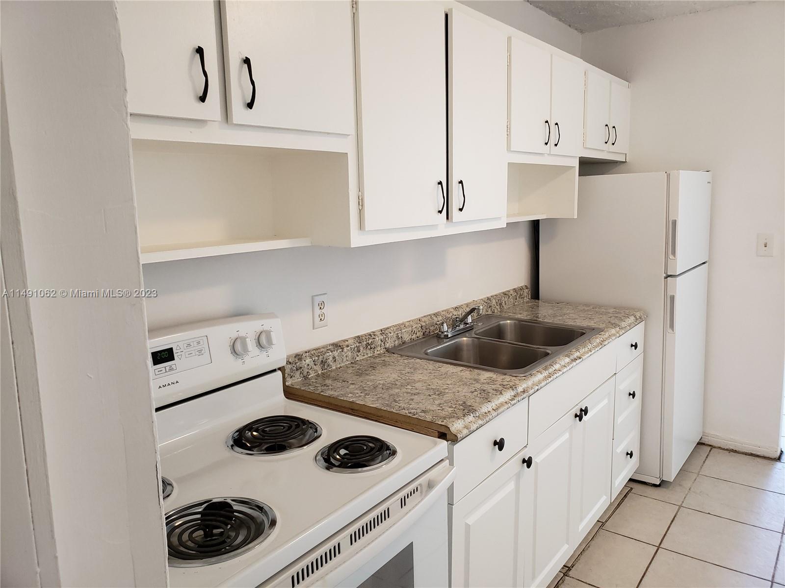 Miami-Dade County Miami, FL 33161 - Photo 19 of 31 a kitchen with white cabinets and white appliances