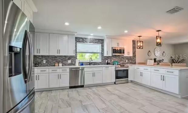 a large kitchen with granite countertop lots of white stainless steel appliances granite countertop lots of white cabinets a stove and sink