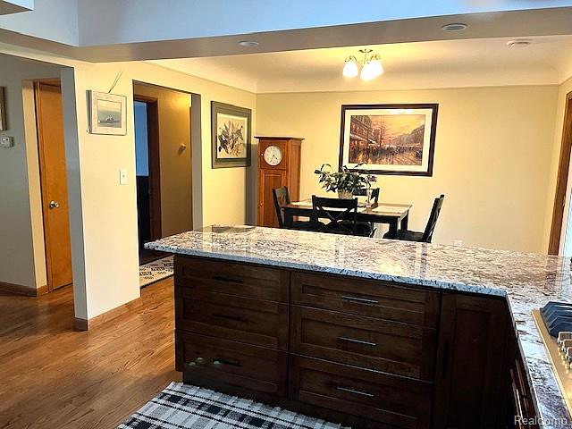 20285 29 Mile Road Ray, MI 48096 - Photo 10 of 25 Kitchen island with a light-toned countertop, dark wood-finish cabinetry, and integrated cooktop