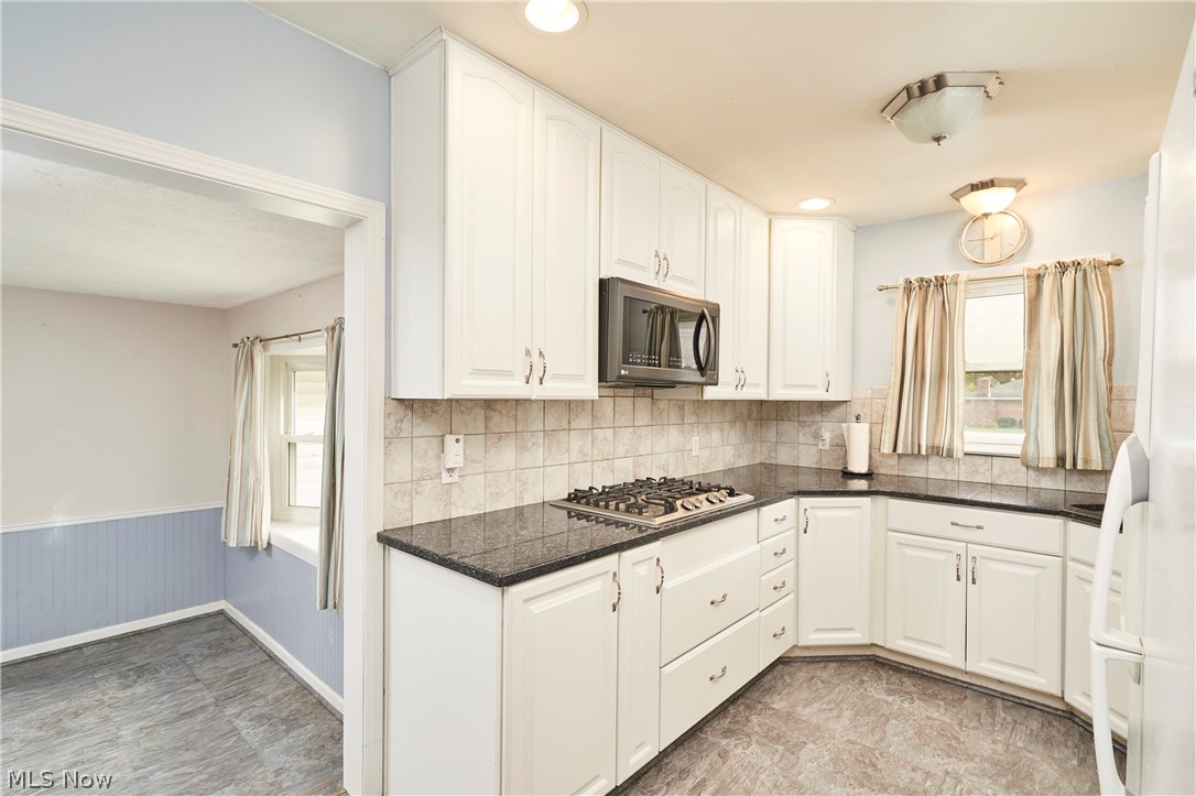 2941 Sweitzer Road Uniontown, OH 44685 - Photo 5 of 16 Kitchen with appliances with stainless steel finishes, white cabinets, wainscoting, decorative backsplash, and dark stone countertops