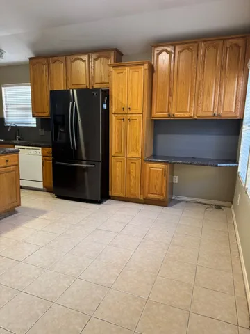 a kitchen with granite countertop a refrigerator a sink and wooden cabinets
