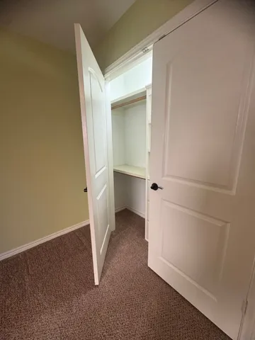 an empty room with a ceiling fan and carpet