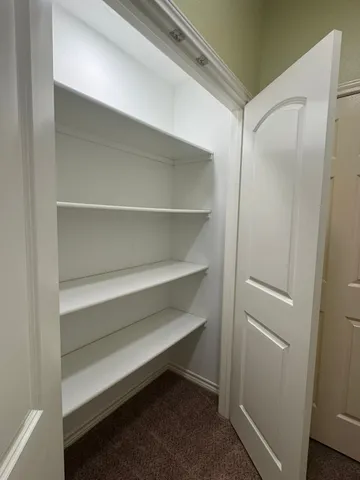 a view of an empty room with wooden floor and closet