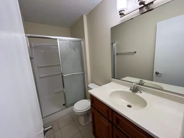 a bathroom with a sink a toilet a mirror and shower