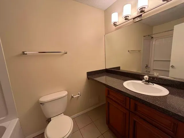 a bathroom with a granite countertop sink toilet and a mirror