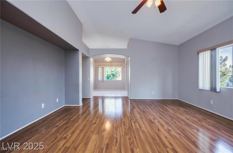 Spare room with dark wood-type flooring, arched walkways, and a ceiling fan