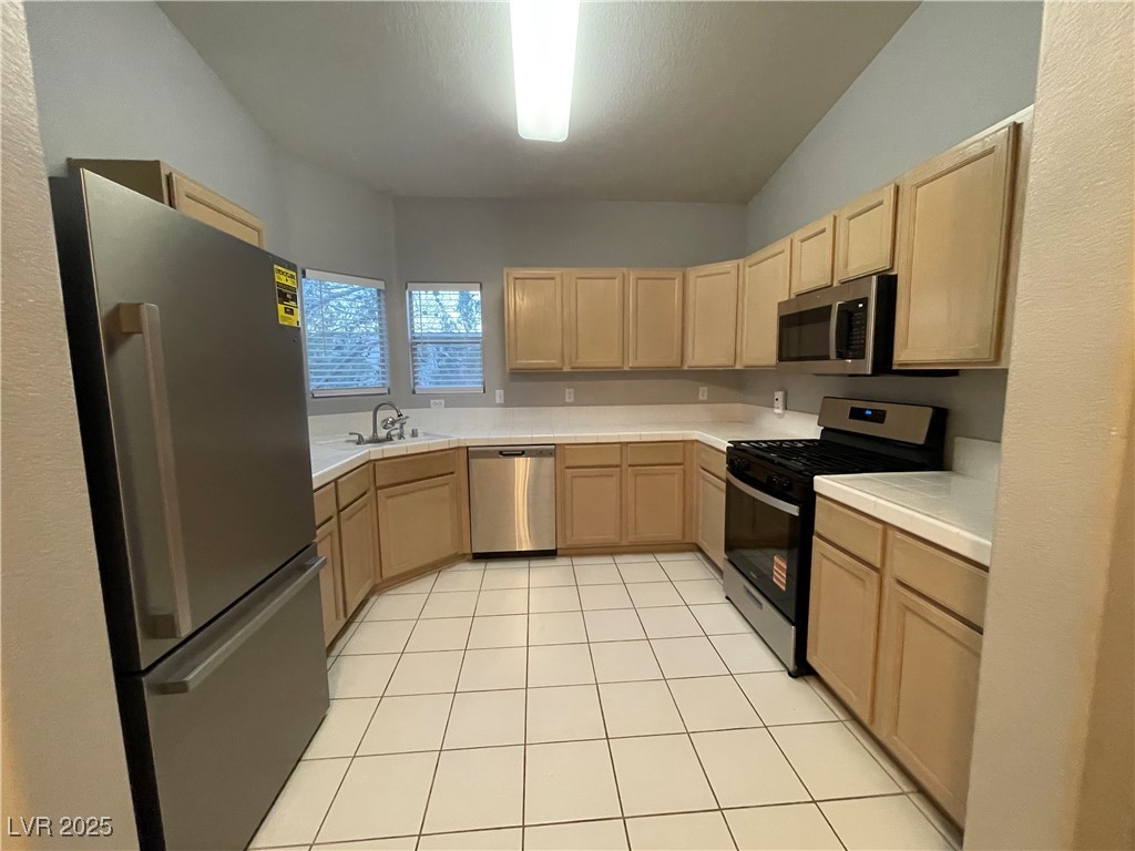 2152 Turquoise Ridge Street, Unit 202 Las Vegas, NV 89117 - Photo 12 of 23 Kitchen with light brown cabinets, appliances with stainless steel finishes, light tile patterned floors, and tile counters
