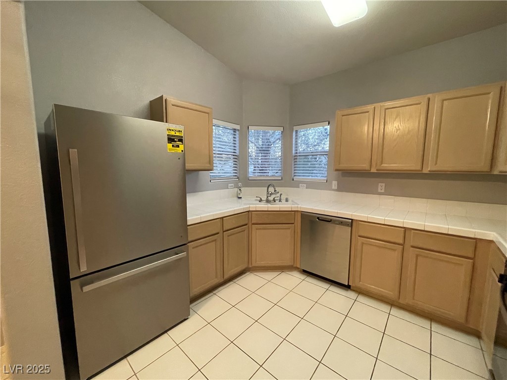 2152 Turquoise Ridge Street, Unit 202 Las Vegas, NV 89117 - Photo 13 of 23 Kitchen with brand new appliances with stainless steel finishes, tile counters, light brown cabinets, and light tile patterned floors