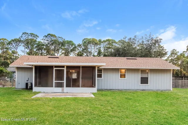 a view of a yard in front of a house with a large tree