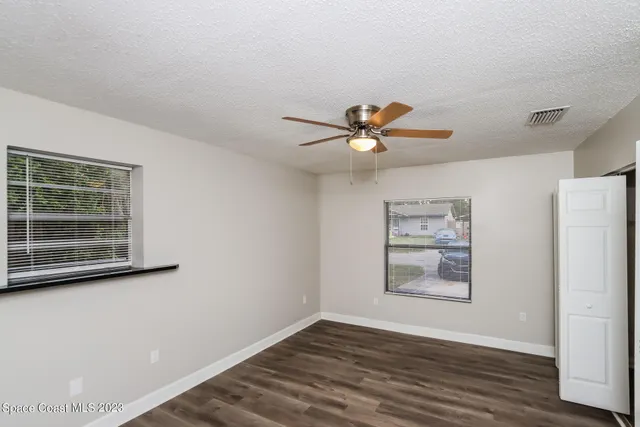 a view of a livingroom with wooden floor and a ceiling fan