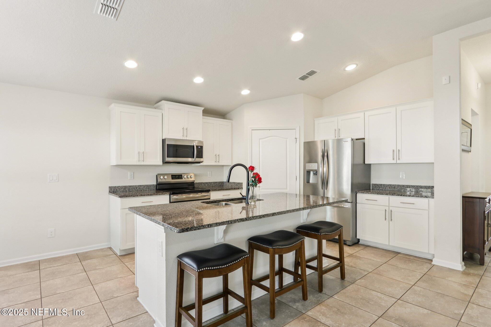 4100 Spring Creek Lane Middleburg, FL 32068 - Photo 12 of 58 a kitchen with stainless steel appliances granite countertop a stove top oven a sink dishwasher and a refrigerator with wooden floor