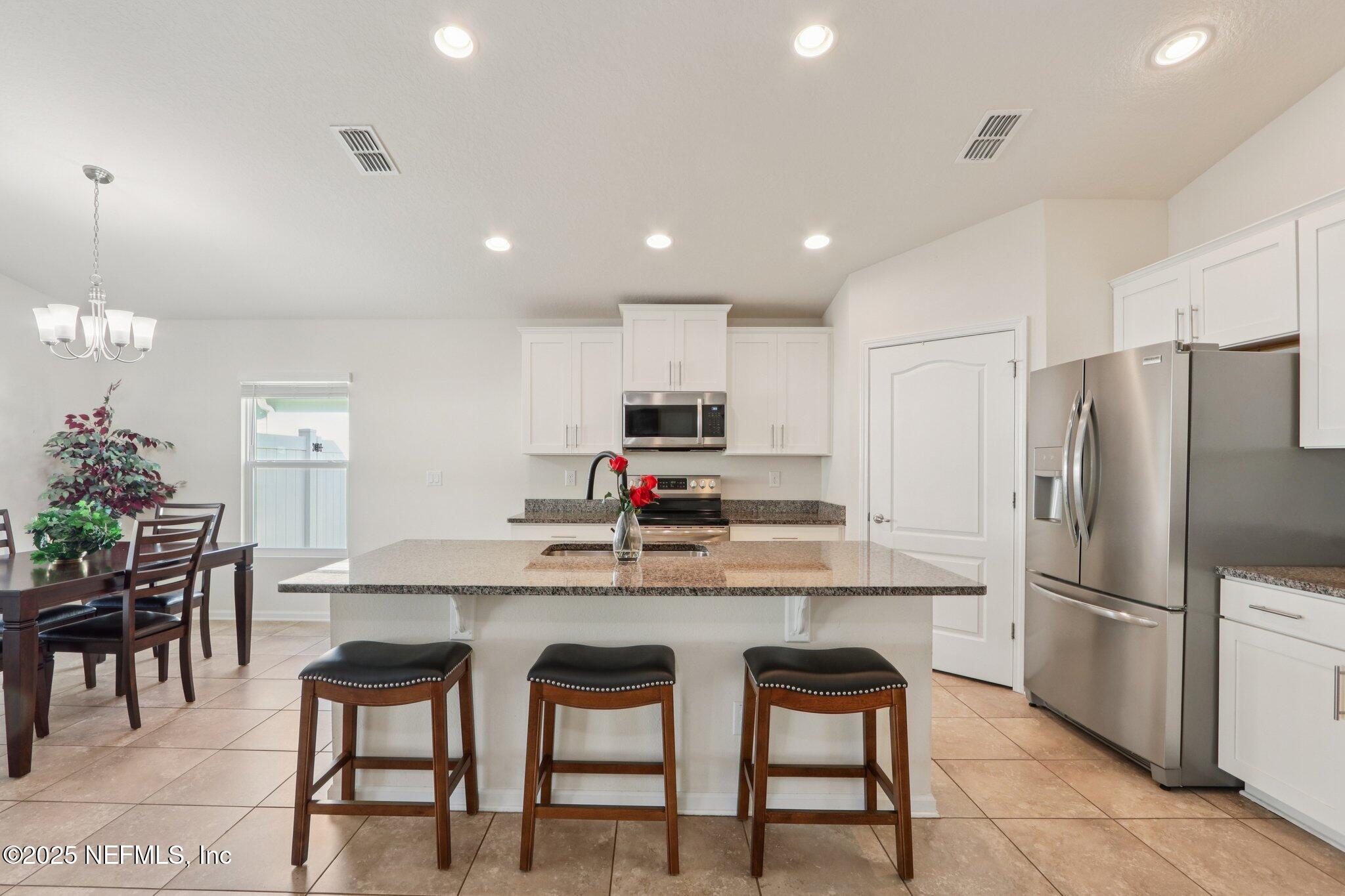 4100 Spring Creek Lane Middleburg, FL 32068 - Photo 16 of 58 a kitchen with refrigerator cabinets dining table and chairs