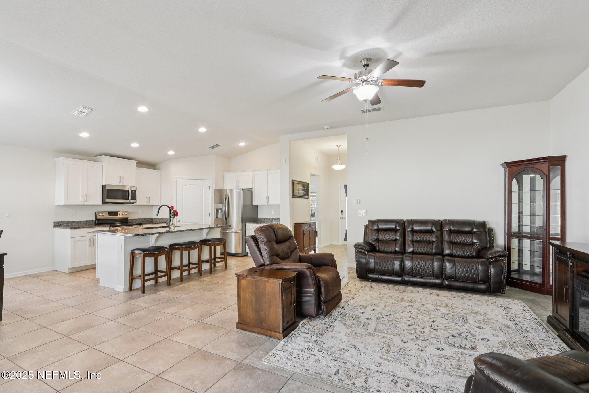 4100 Spring Creek Lane Middleburg, FL 32068 - Photo 8 of 58 a living room with stainless steel appliances furniture a rug and a view of kitchen