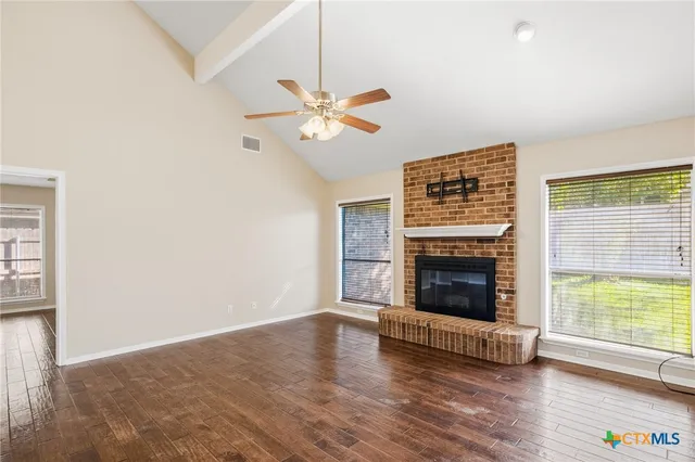 a view of a livingroom with a fireplace a ceiling fan and wooden floor
