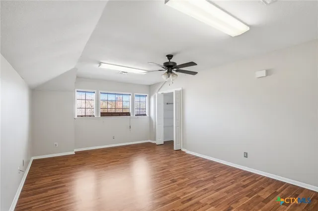 a view of empty room with wooden floor and fan