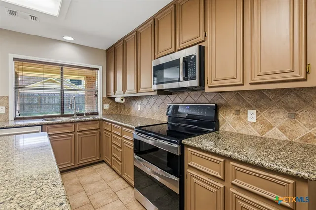 a kitchen with granite countertop a stove sink and microwave