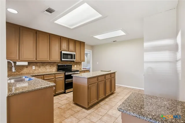 a kitchen with stainless steel appliances granite countertop a stove top oven a sink a microwave and refrigerator