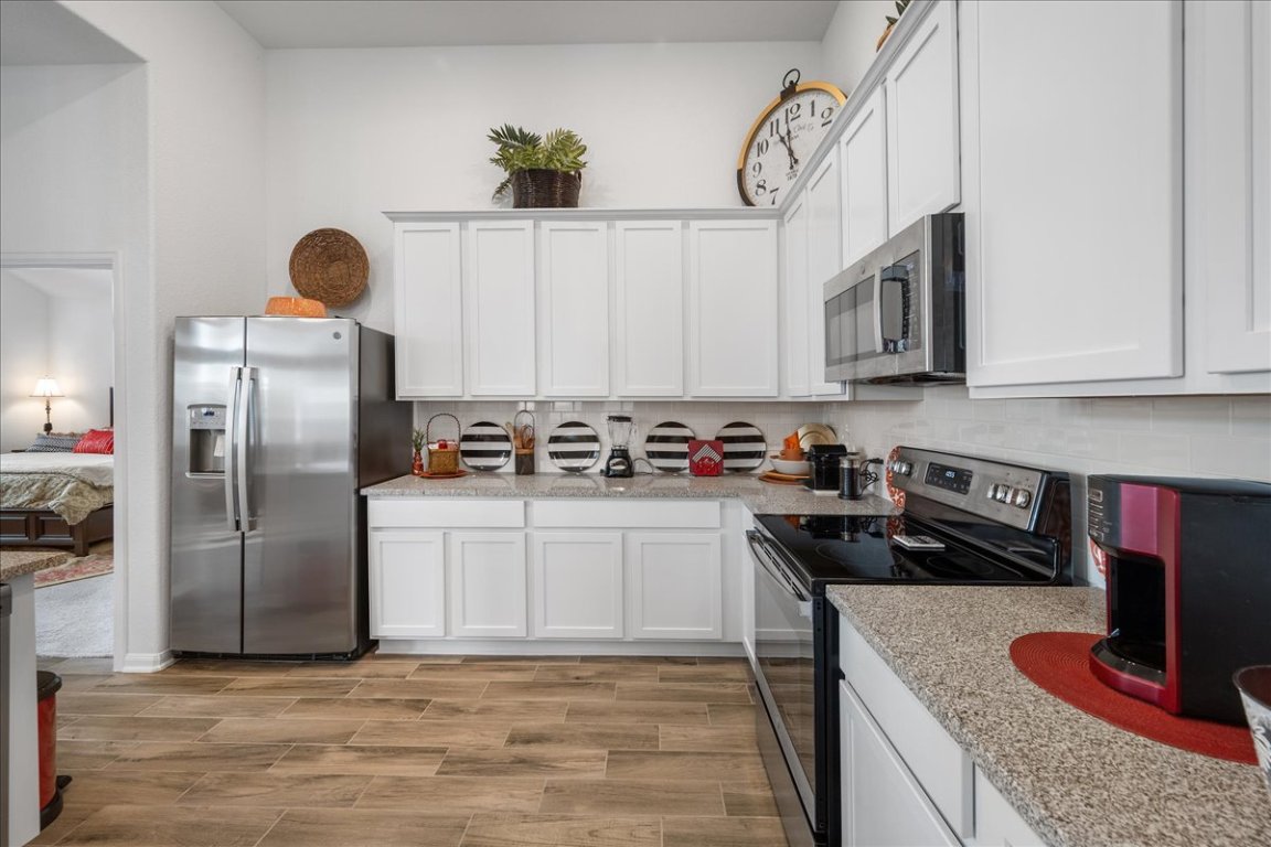 181 Durian Loop Buda, TX 78610 - Photo 8 of 22 a kitchen with stainless steel appliances granite countertop a sink a stove and a refrigerator