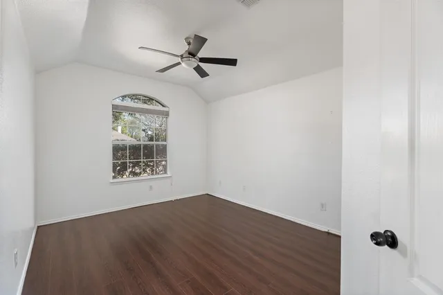 an empty room with wooden floor fan and windows